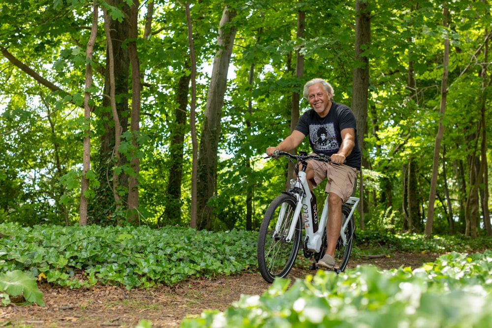 a man riding a bike through a lush green forest