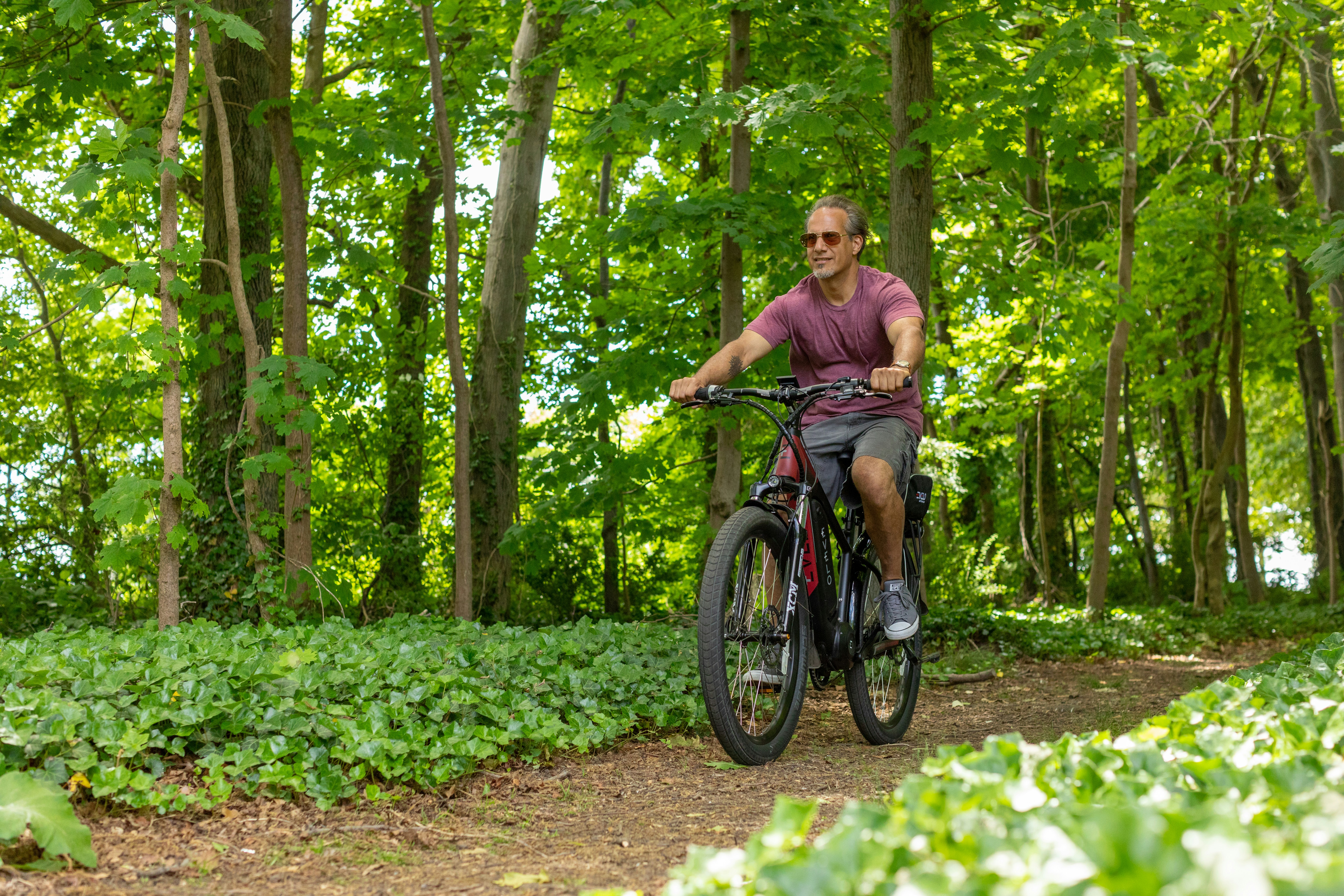 a man riding a bike through a lush green forest