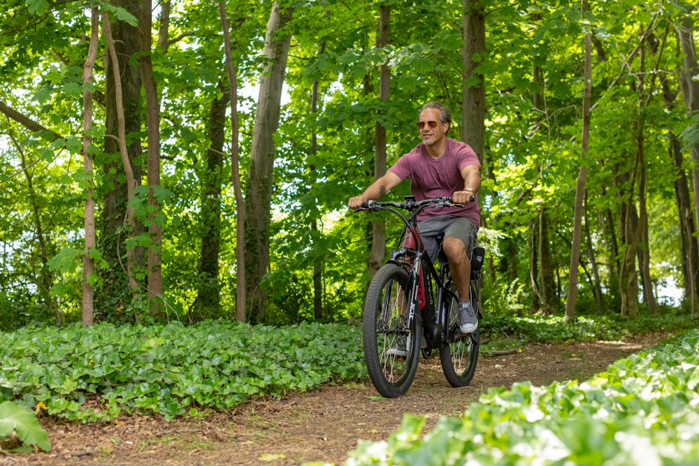 a man riding a bike through a lush green forest