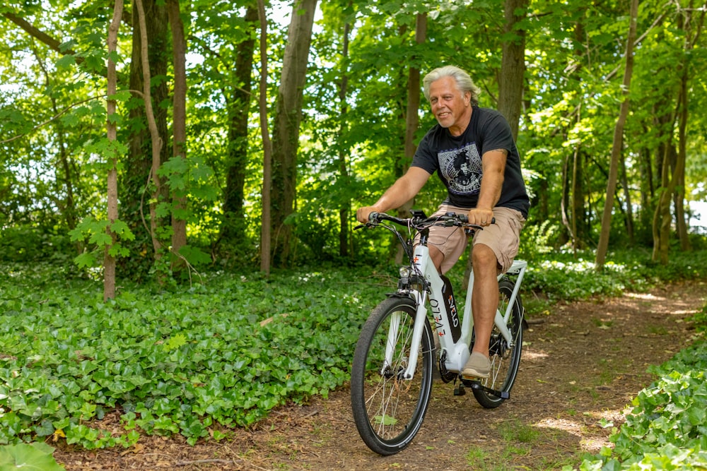 a man riding a bike through a lush green forest