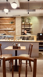 A warm, inviting cafe interior with wooden tables, soft lighting, and a barista preparing coffee behind the counter.