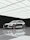A silver luxury car parked inside a minimalist, high-tech detailing studio with carbon fiber accents.