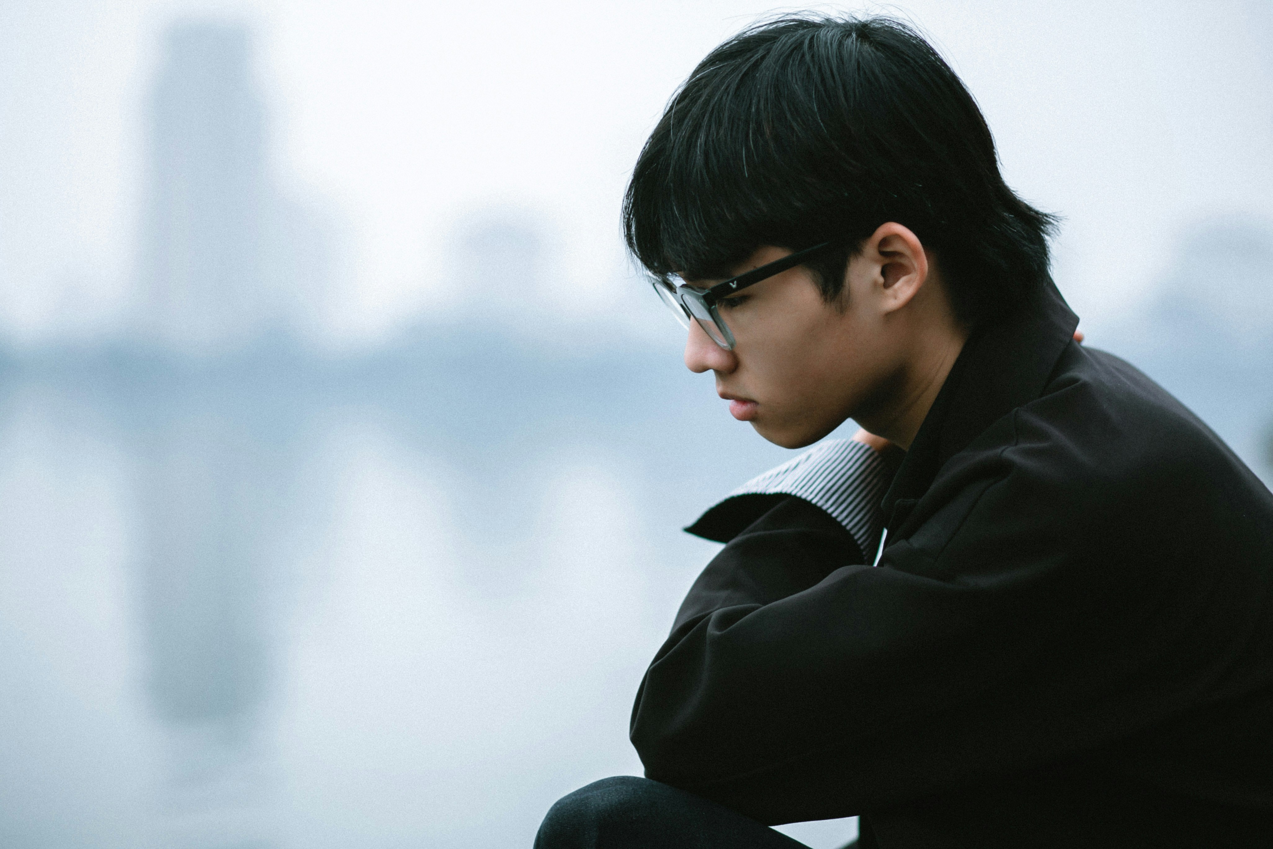 a man sitting on a ledge looking at the water