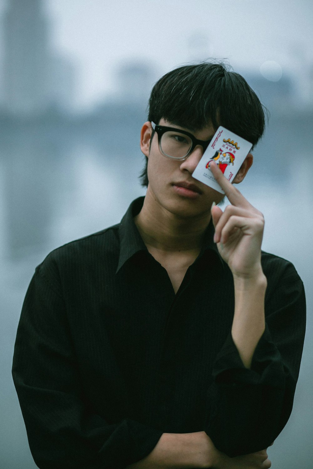a man with glasses holding a card in front of his face