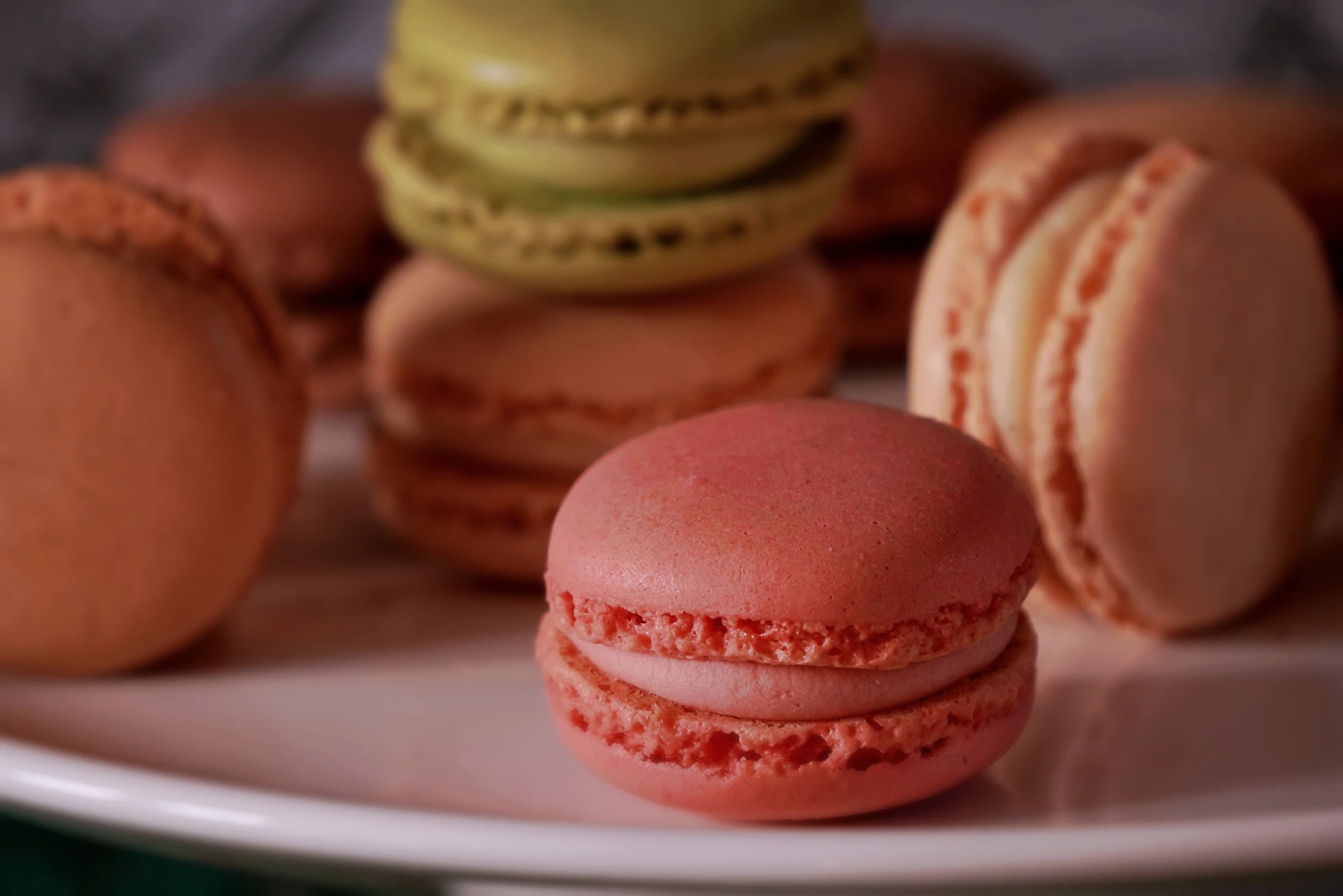 a white plate topped with lots of pink and green macaroons