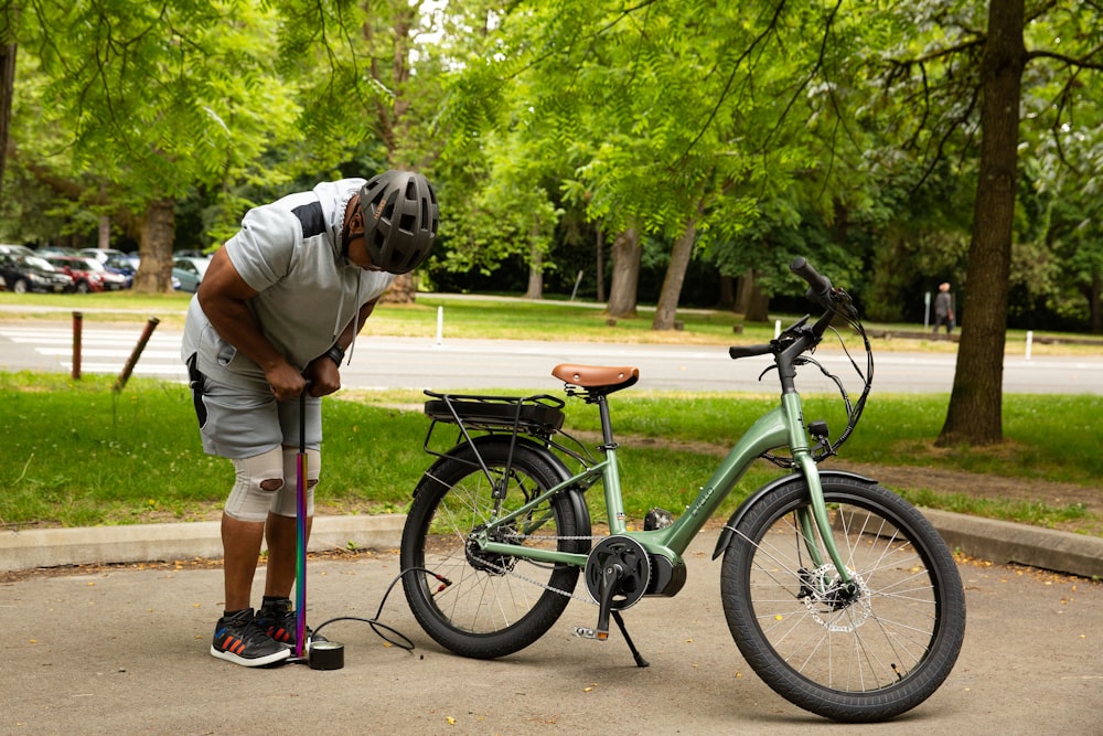 a man is leaning on a bike on the side of the road