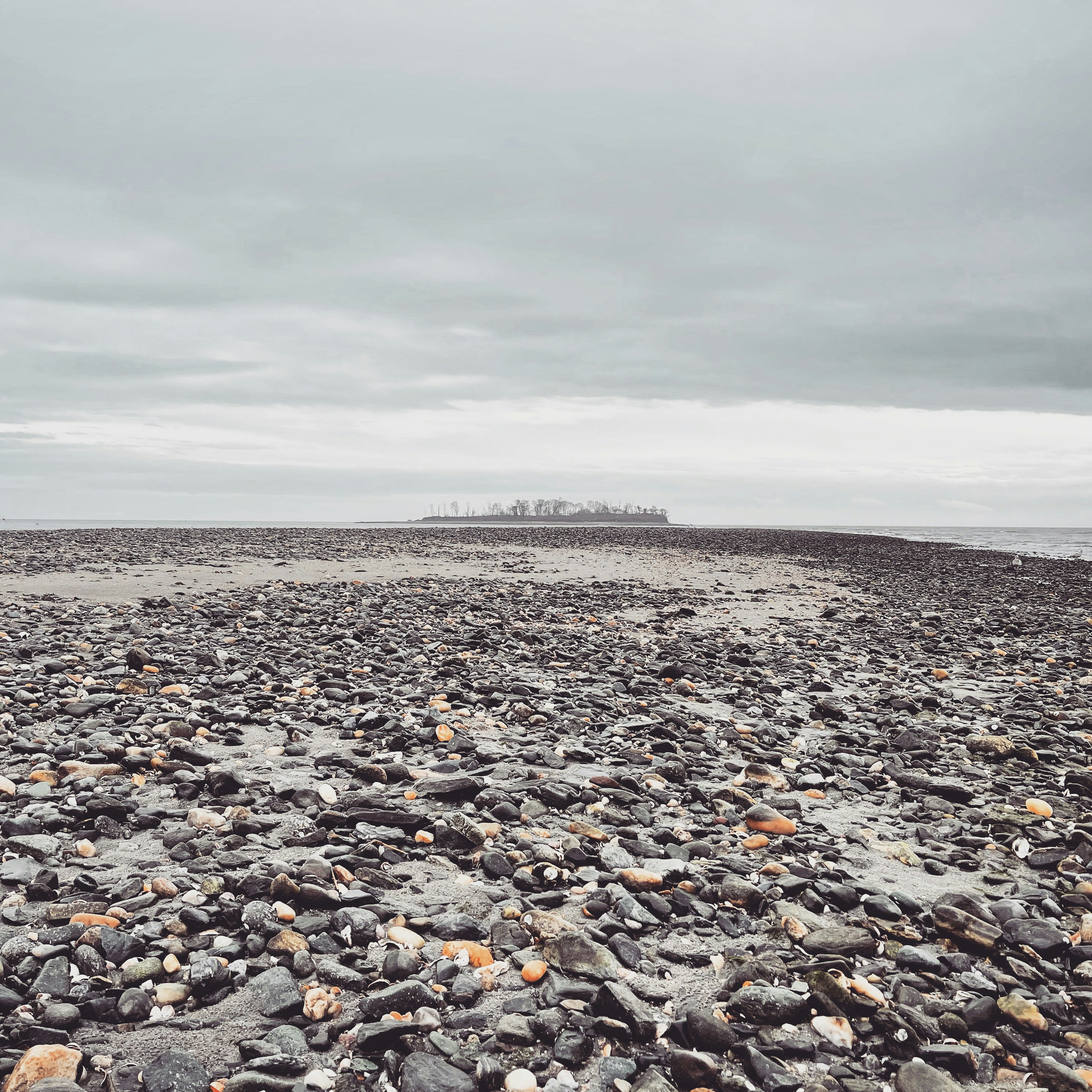 a rocky beach with a small island in the distance