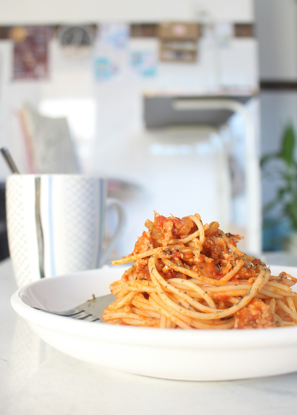 a white bowl filled with spaghetti and sauce