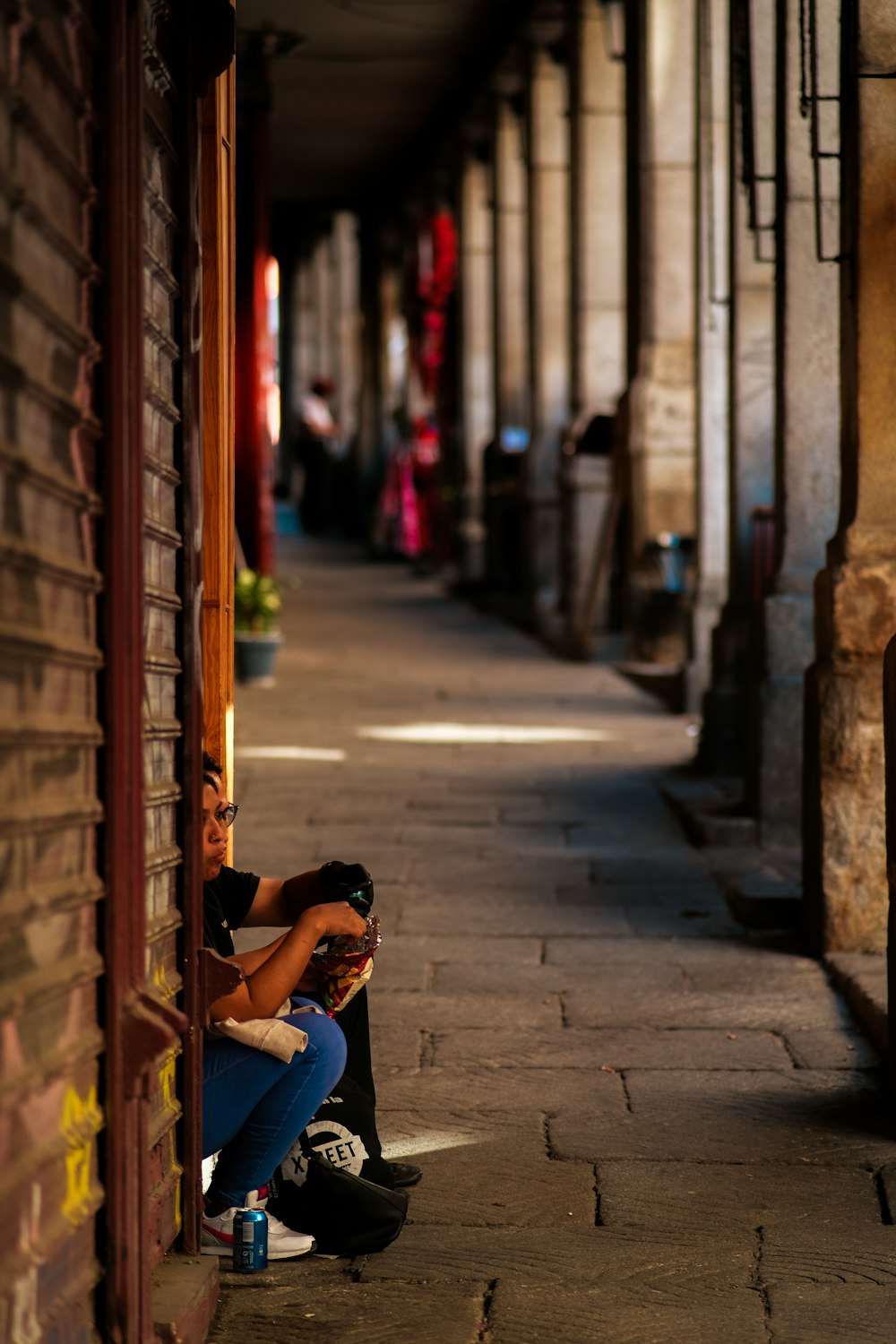 a person sitting on a curb next to a building