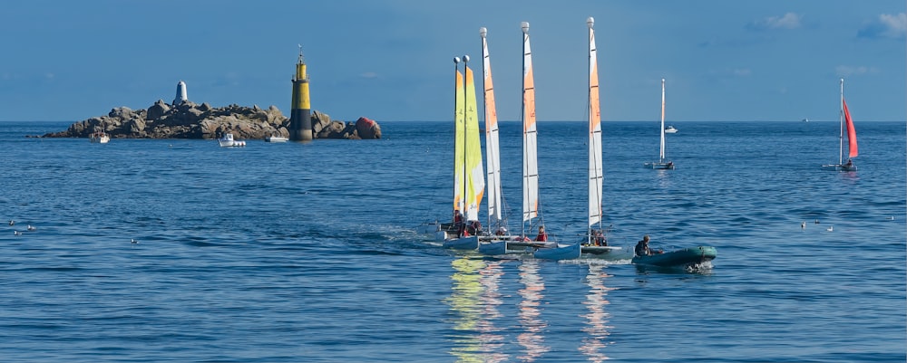 a group of sailboats in the ocean with a small island in the background