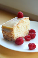 a piece of cake on a plate with raspberries