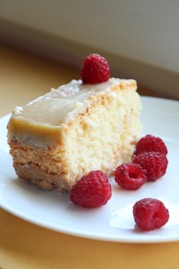 a piece of cake on a plate with raspberries