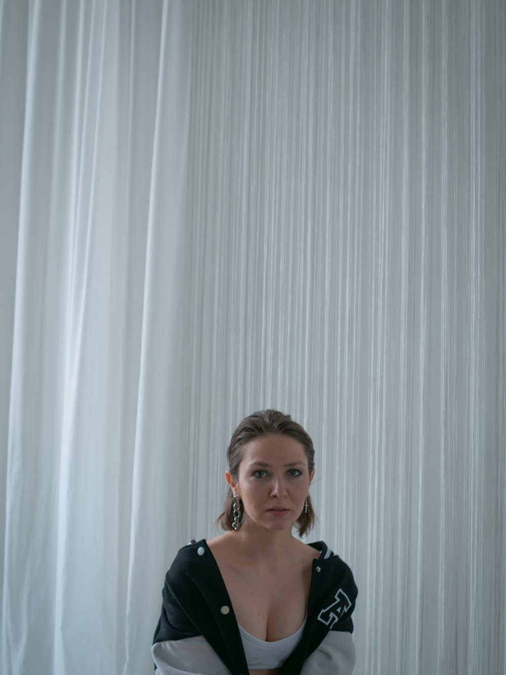 a woman sitting in front of a white curtain