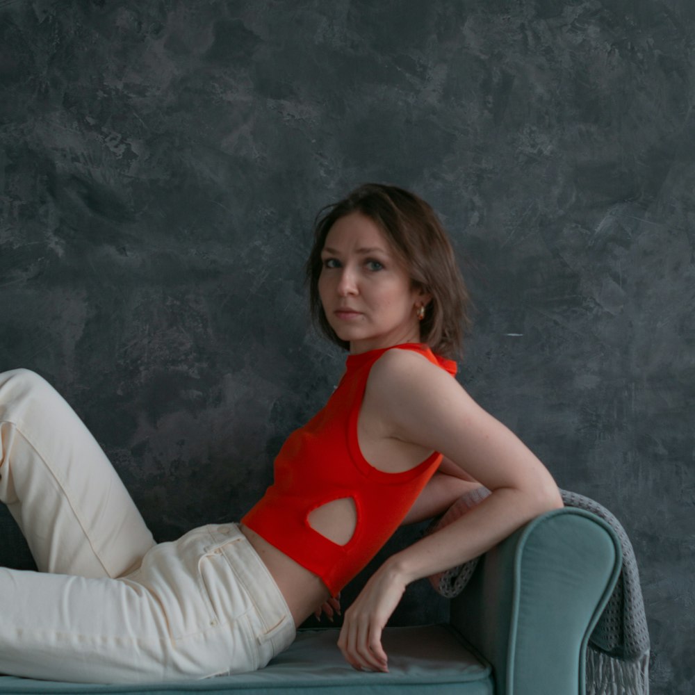 a woman in a red top is sitting on a couch