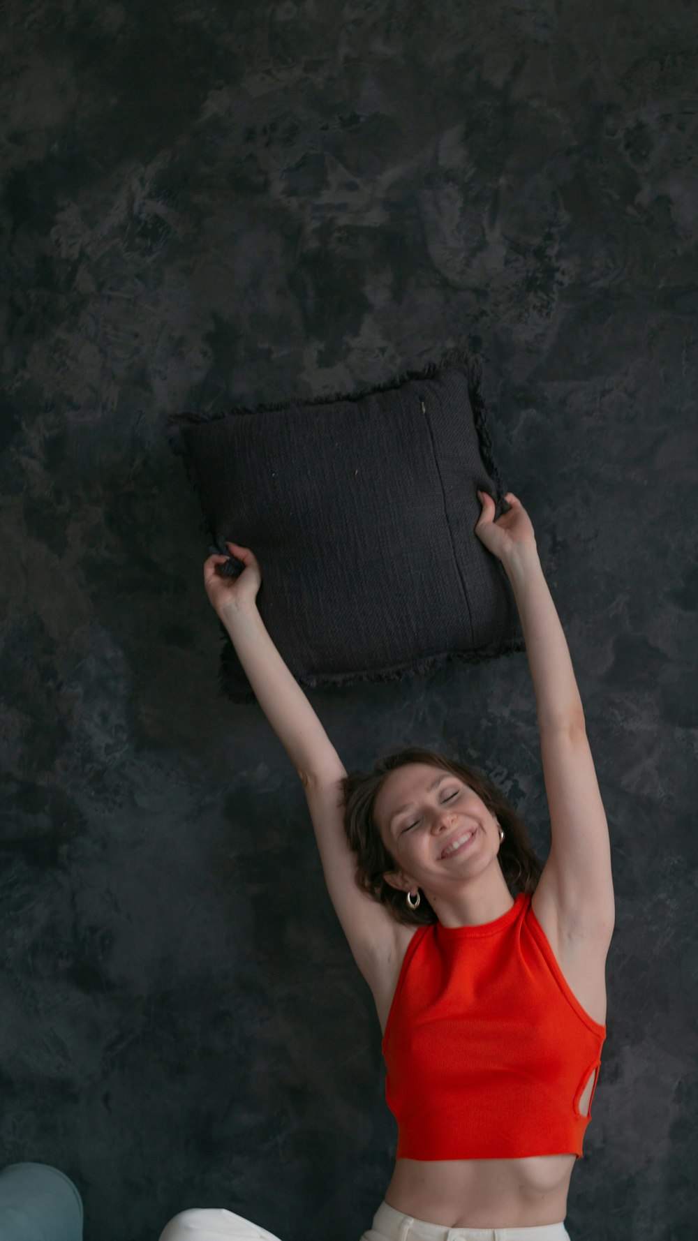 a woman in a red top is holding a black pillow