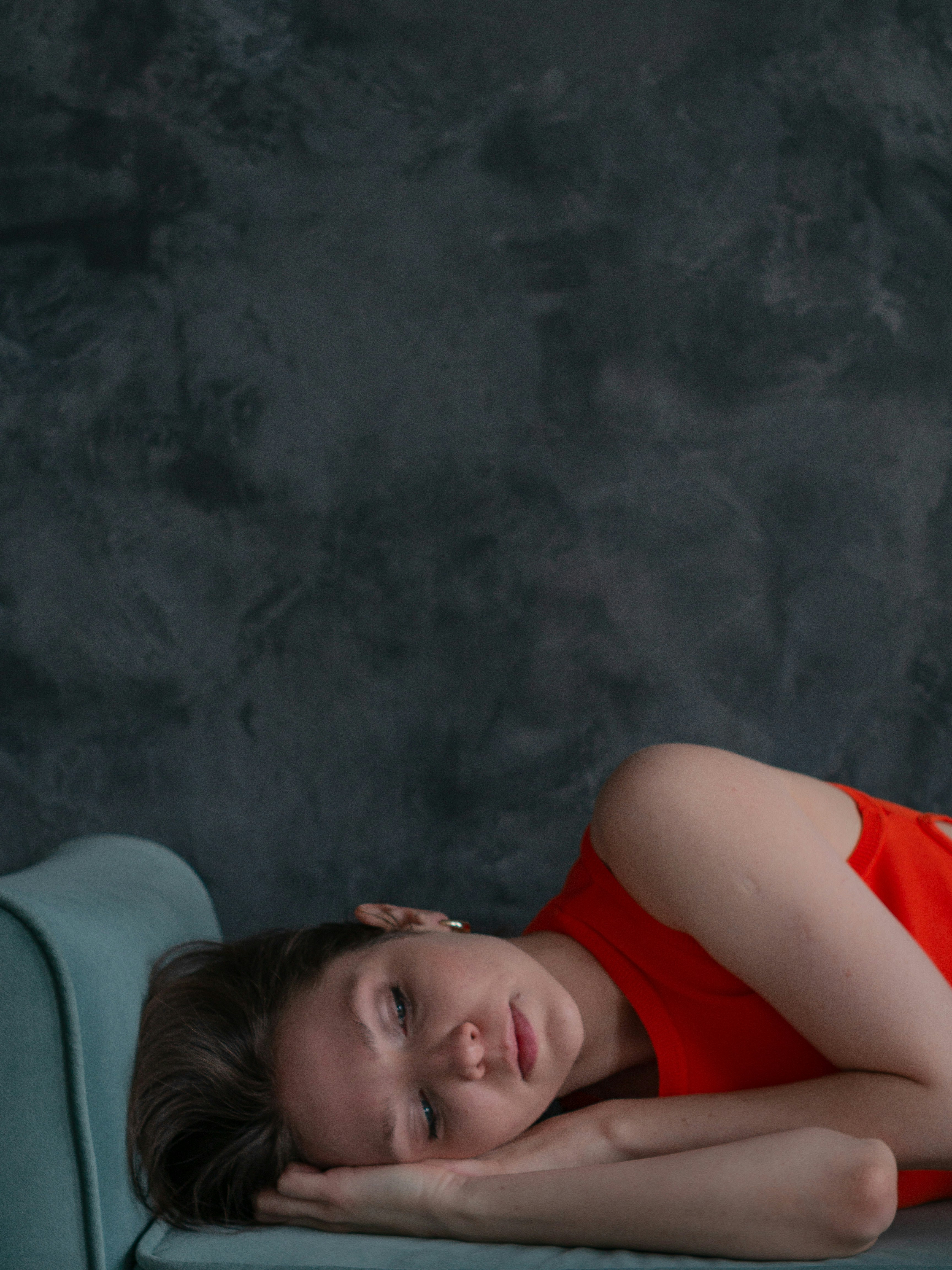 a woman in a red dress laying on a blue couch