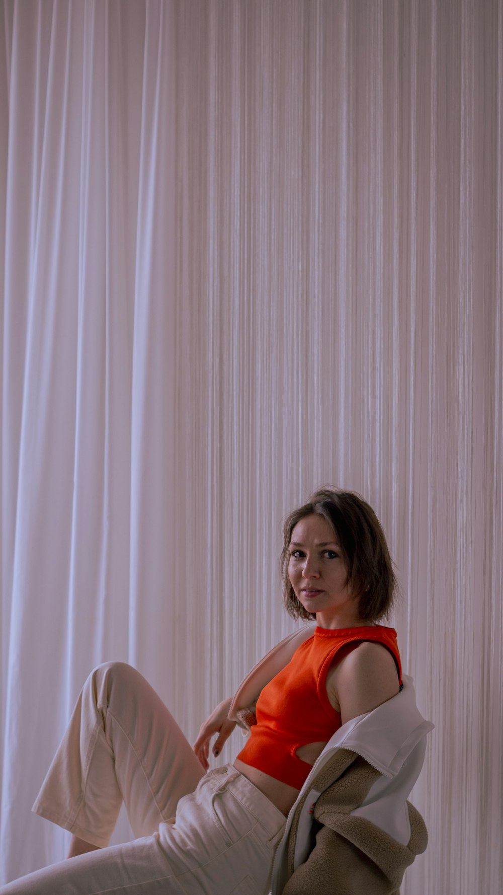 a woman sitting on a chair in front of a curtain