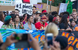 A group of diverse volunteers smiling and holding eco-friendly banners.