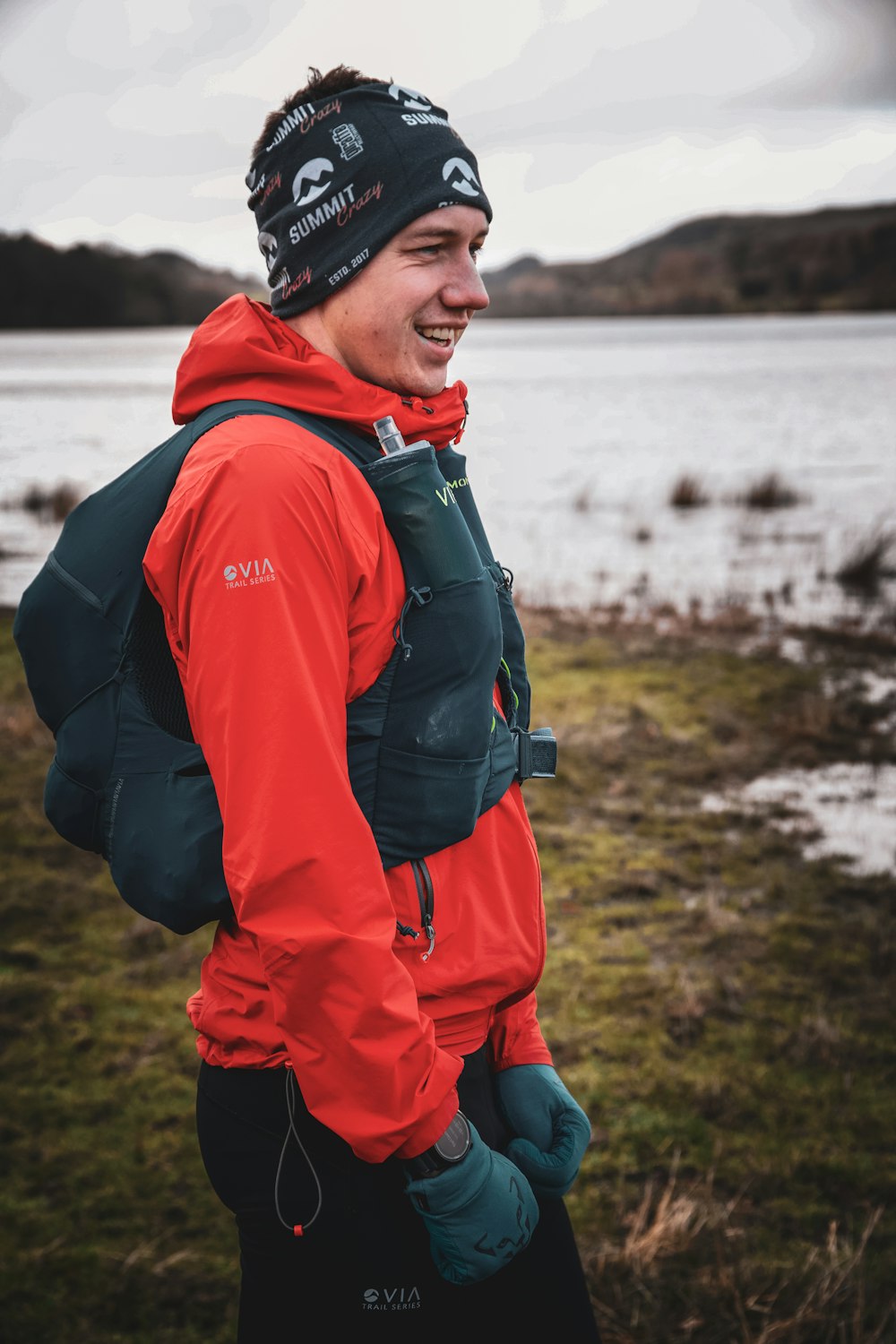 a man wearing a red jacket and a green backpack