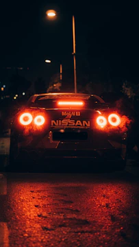 Nighttime urban street scene featuring a sleek sports car with neon red highlights.