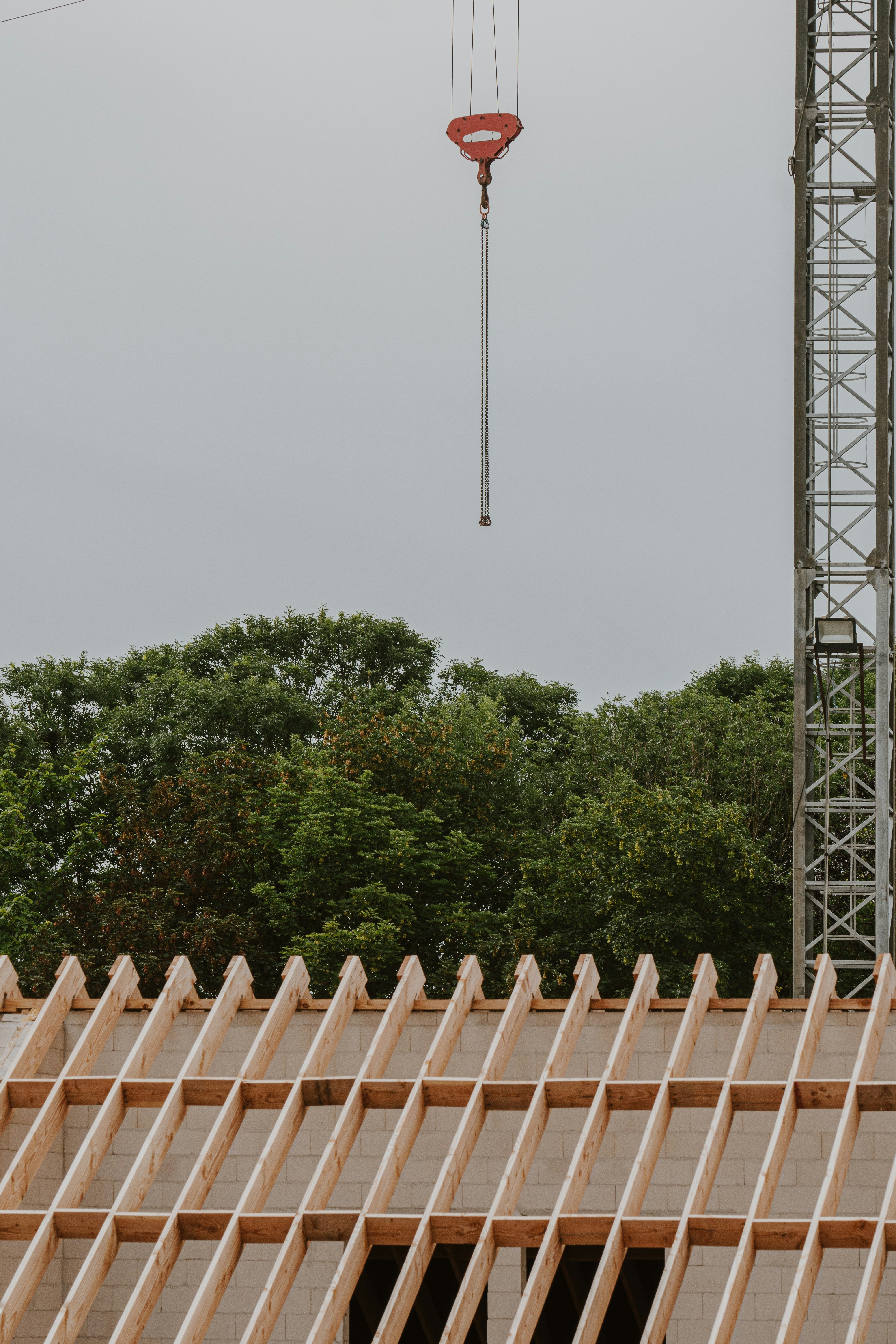 a crane is lifting a piece of wood on top of a building