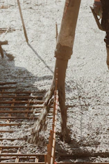 Workers pouring and smoothing fresh concrete foundation at a residential site.