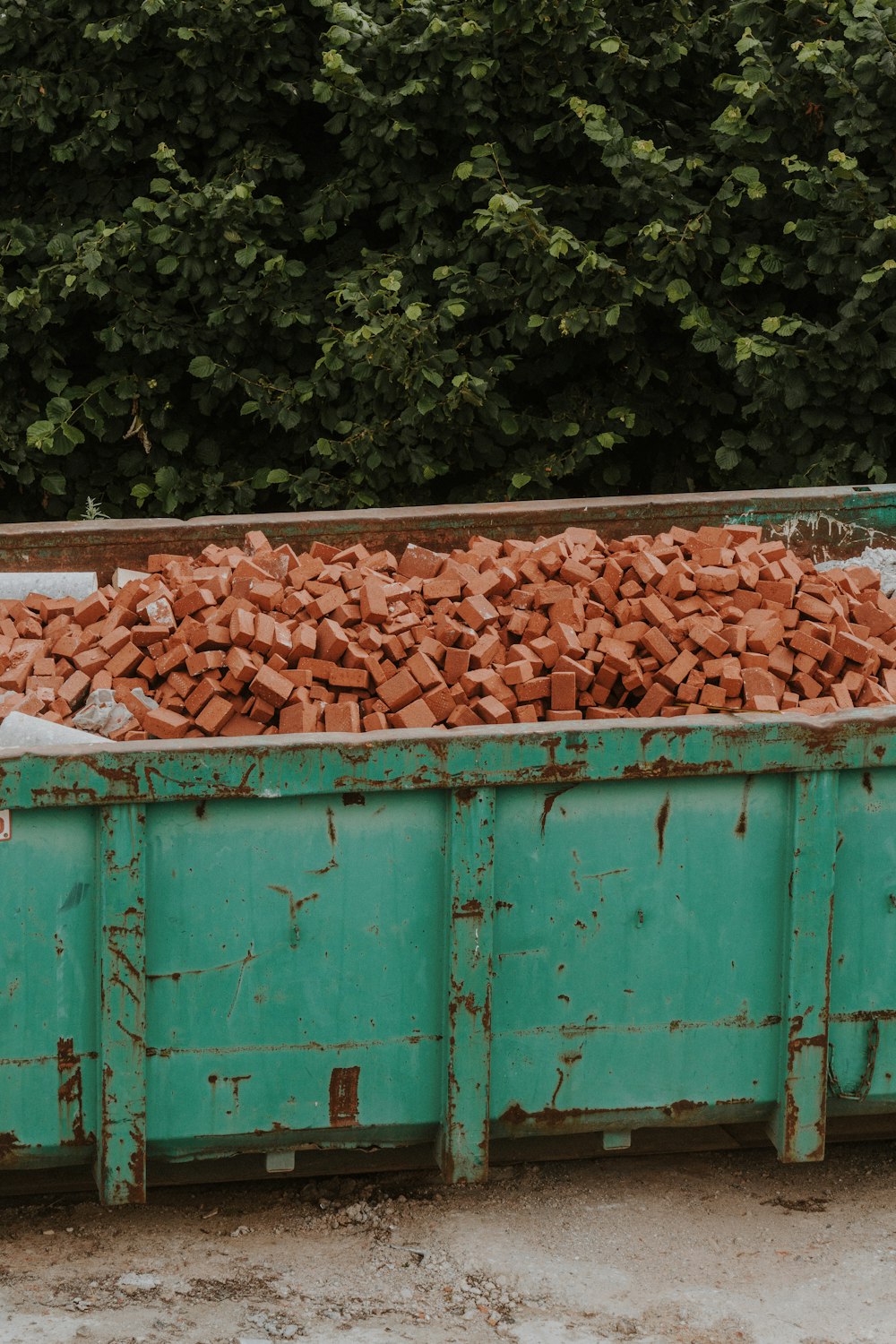 a green dump truck filled with red bricks