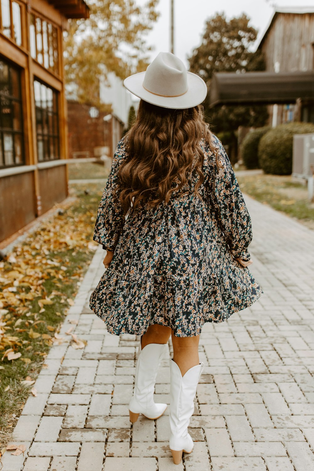 a woman walking down a sidewalk wearing white boots