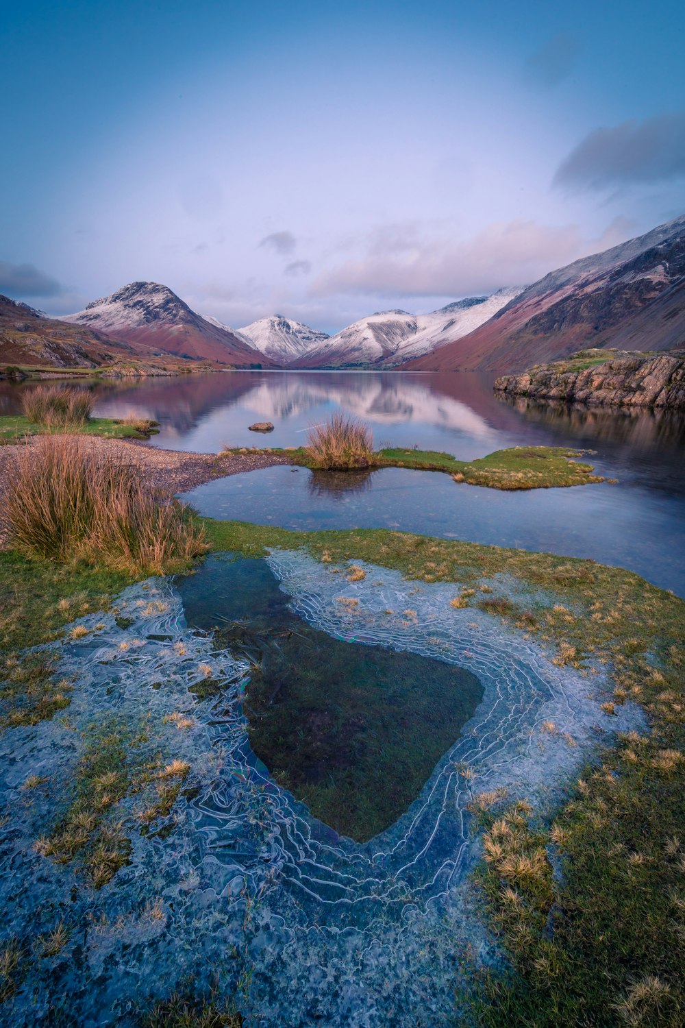 a body of water surrounded by mountains and grass