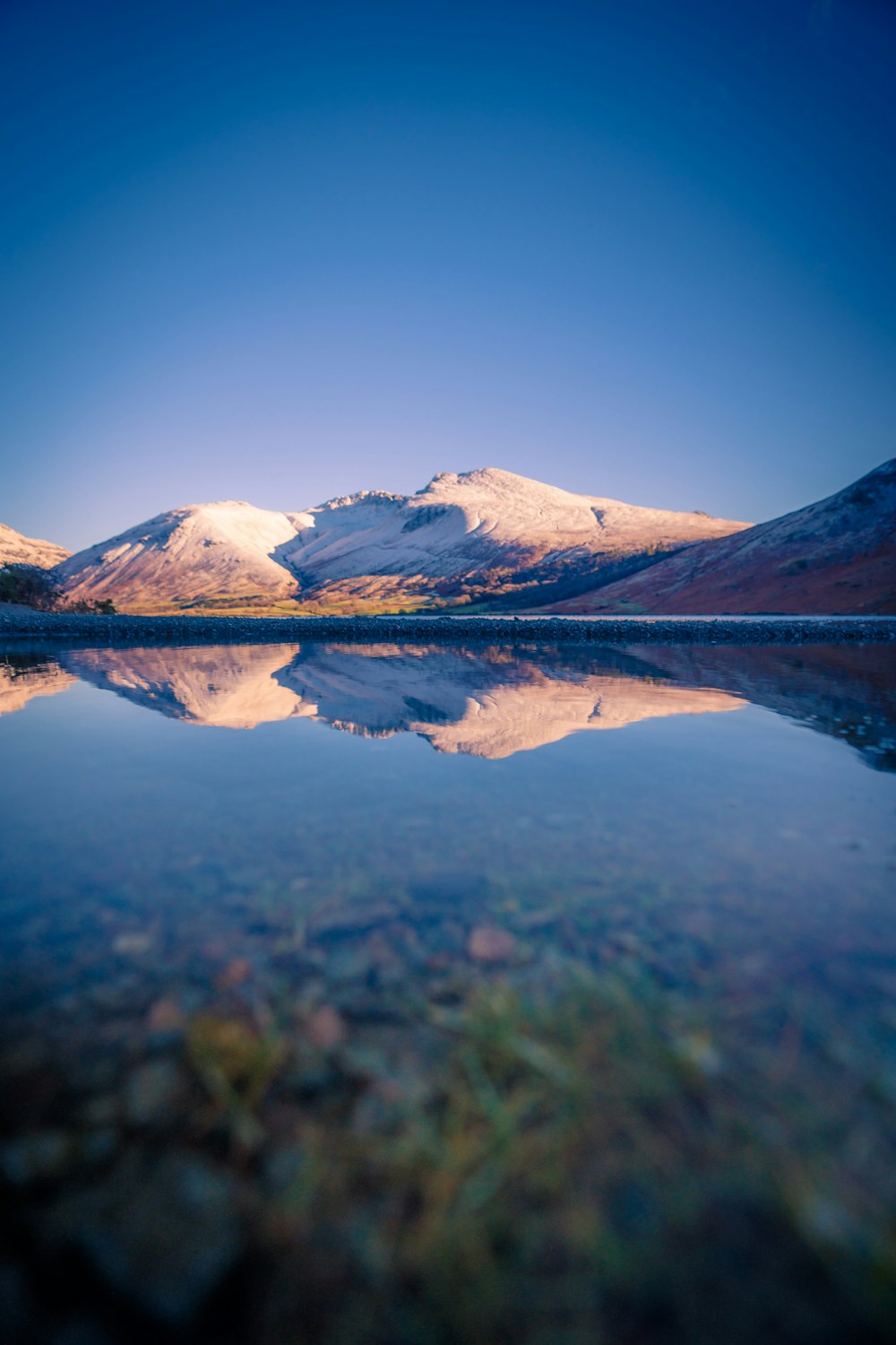 the mountains are reflected in the still water of the lake