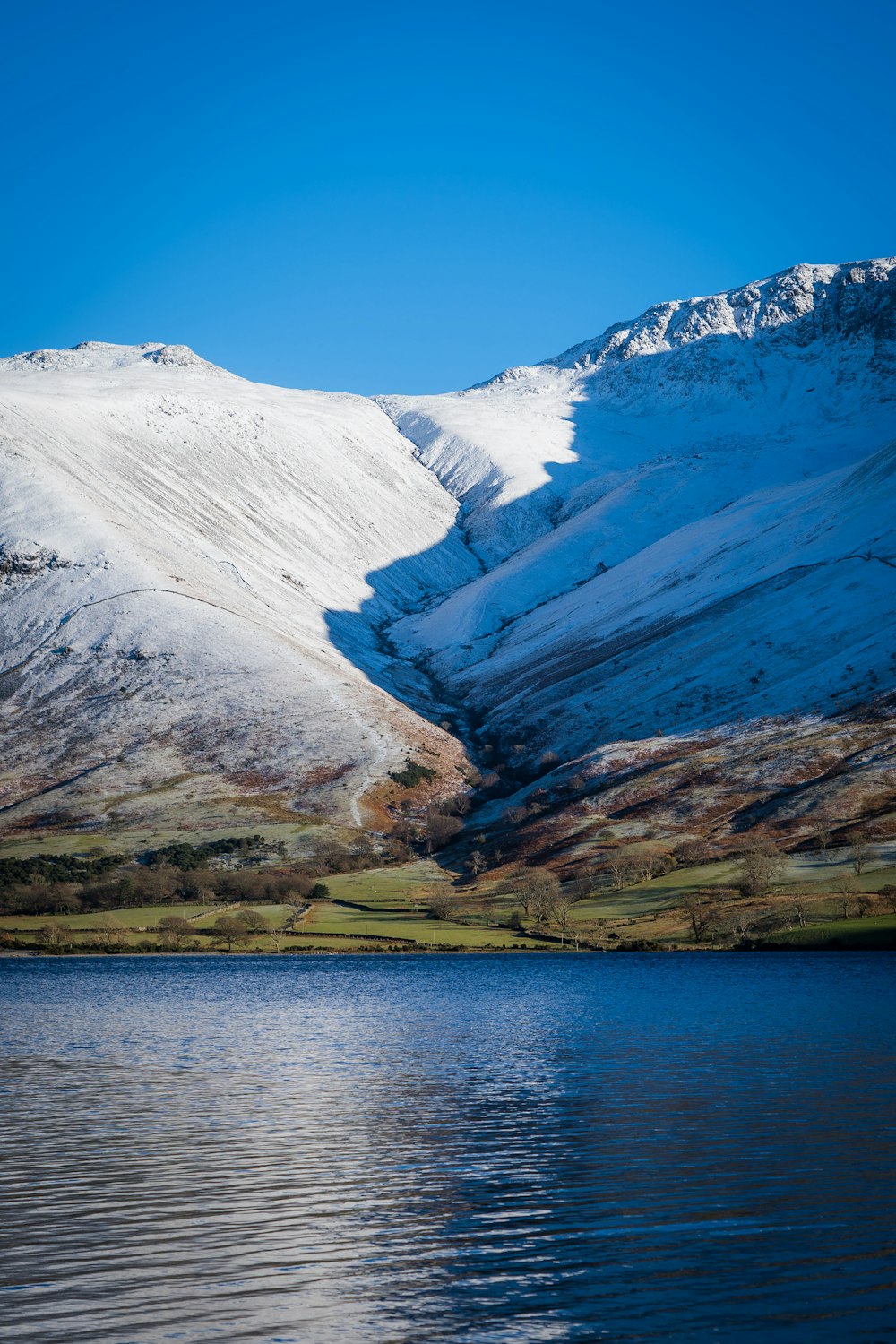 a mountain covered in snow next to a body of water