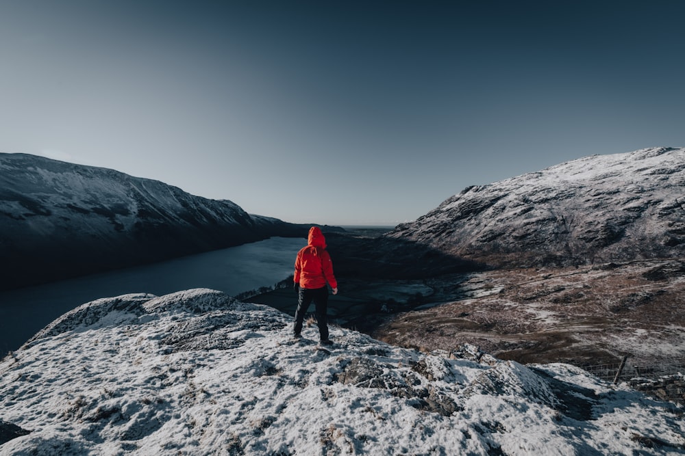 a person in a red jacket standing on a snowy mountain