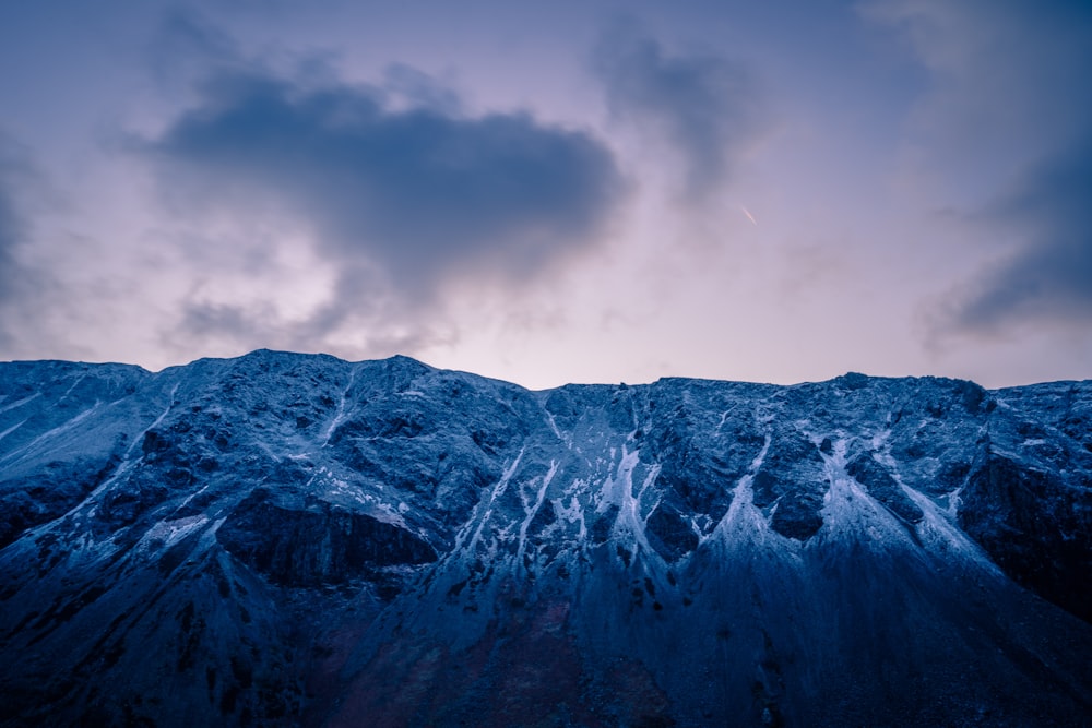 a view of a snow covered mountain with clouds in the sky