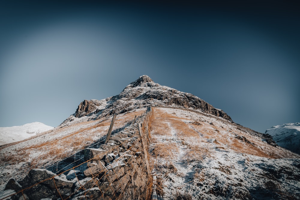 a snow covered mountain with a fence in the foreground