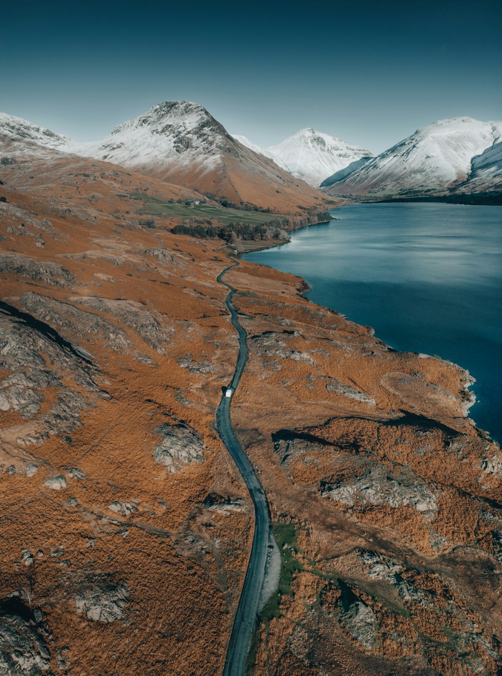 an aerial view of a winding road near a body of water