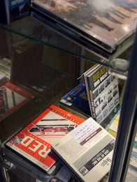 A collection of music CDs and DVDs is displayed on glass shelves. Visible titles include 'Beatles Big Beat Box' and 'Red', among others, with some featuring band images and artistic designs. The arrangement is neat, with a focus on showcasing music memorabilia.