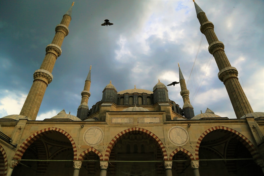 a bird flying over a building with arches and arches