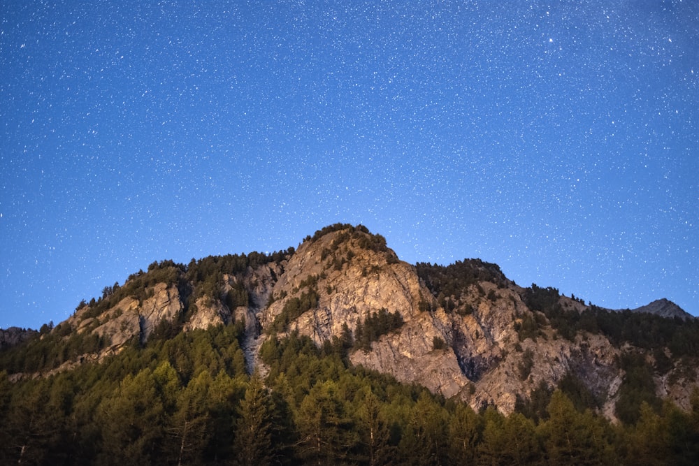 the night sky over a mountain with stars above it