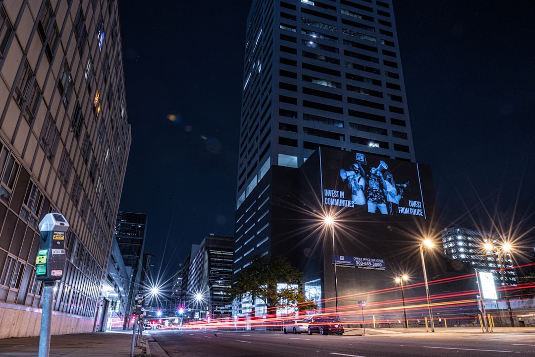 a city street at night with a tall building in the background,
