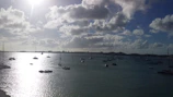 A wide view of a calm bay with sailboats resting near the shore.