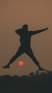 An artistic depiction of a superhero flying over a sunset.