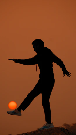 Shadowed silhouette of feet in high heels against a warm sunset backdrop.