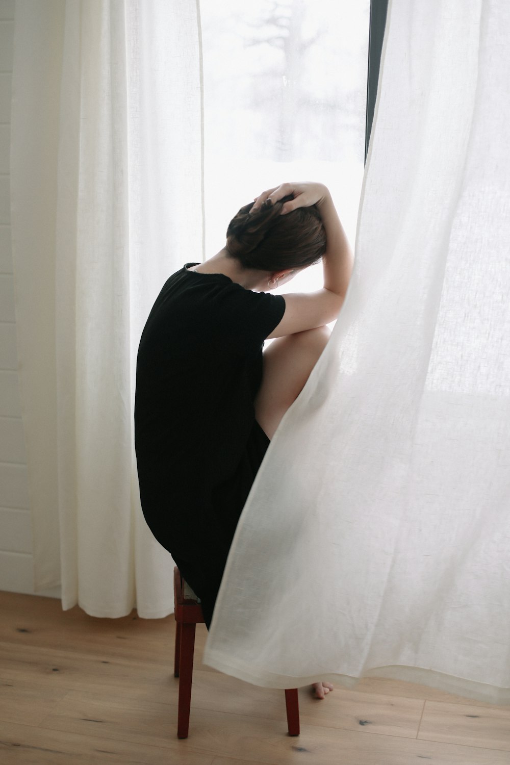 a woman sitting on a chair in front of a window