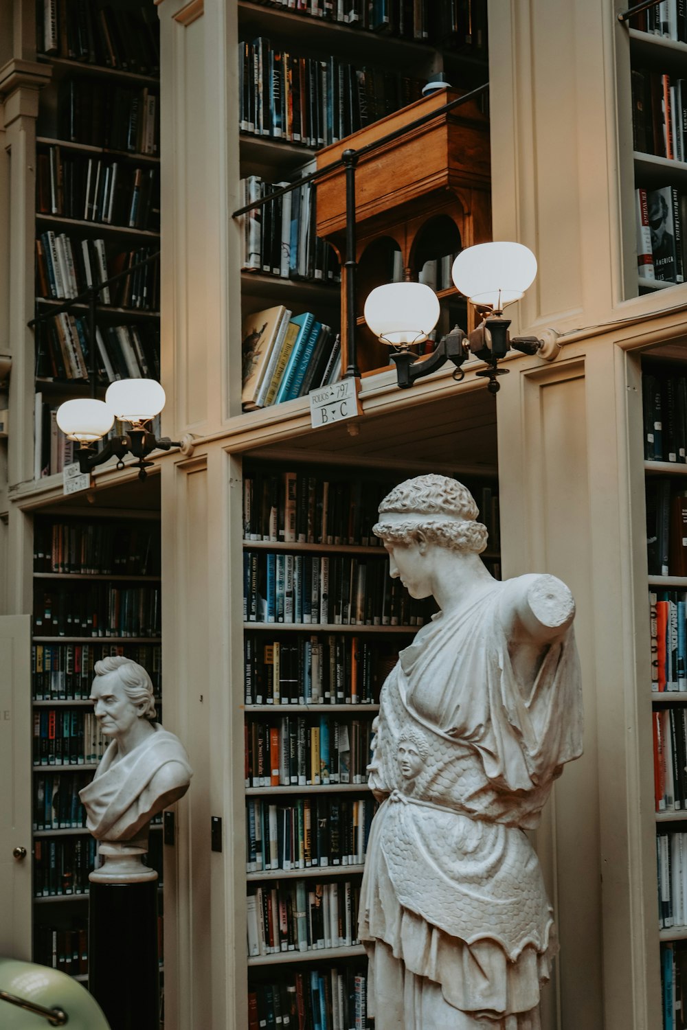 a statue of a woman standing in front of a bookshelf