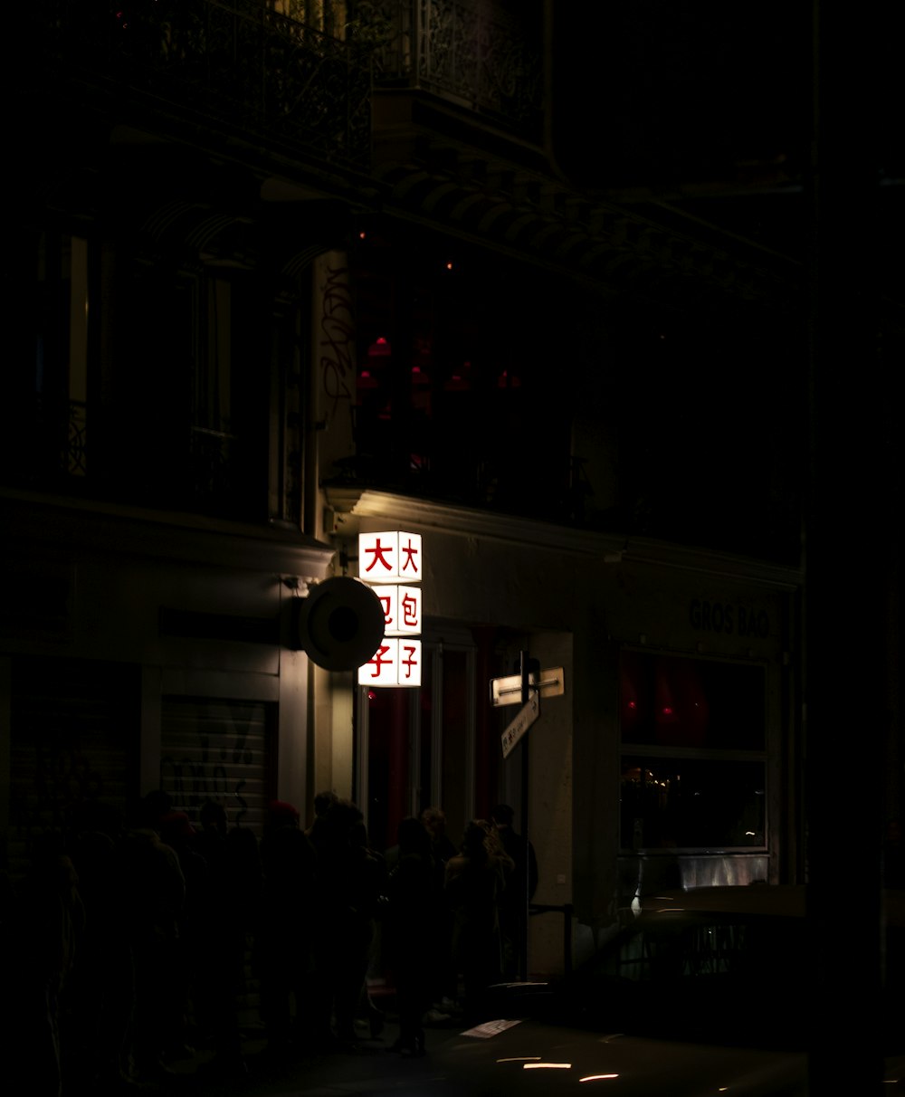 a group of people standing outside of a building at night