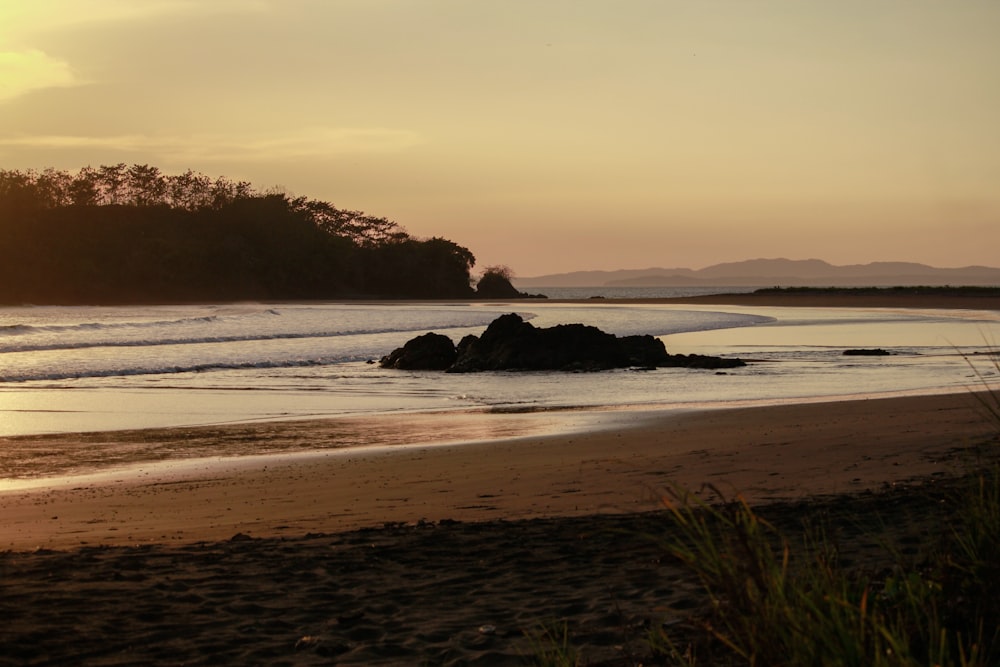 the sun is setting over the water at the beach