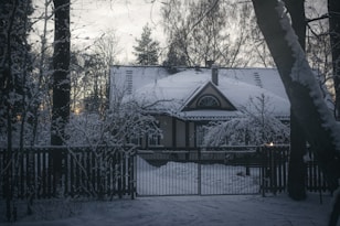 a house covered in snow next to a fence