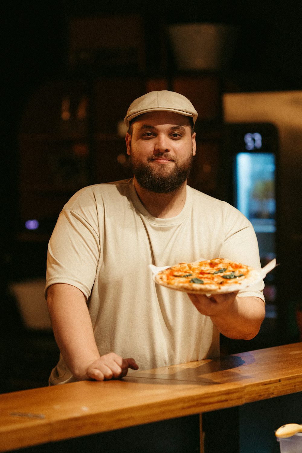 a man holding a pizza on top of a wooden counter