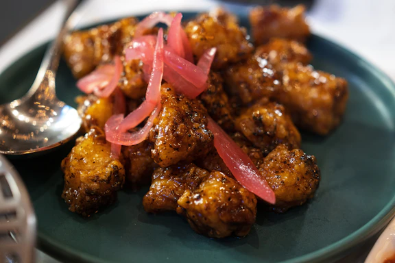 A vibrant plate of golden fried chicken glazed with a glossy sweet soy sauce, garnished with fresh herbs.