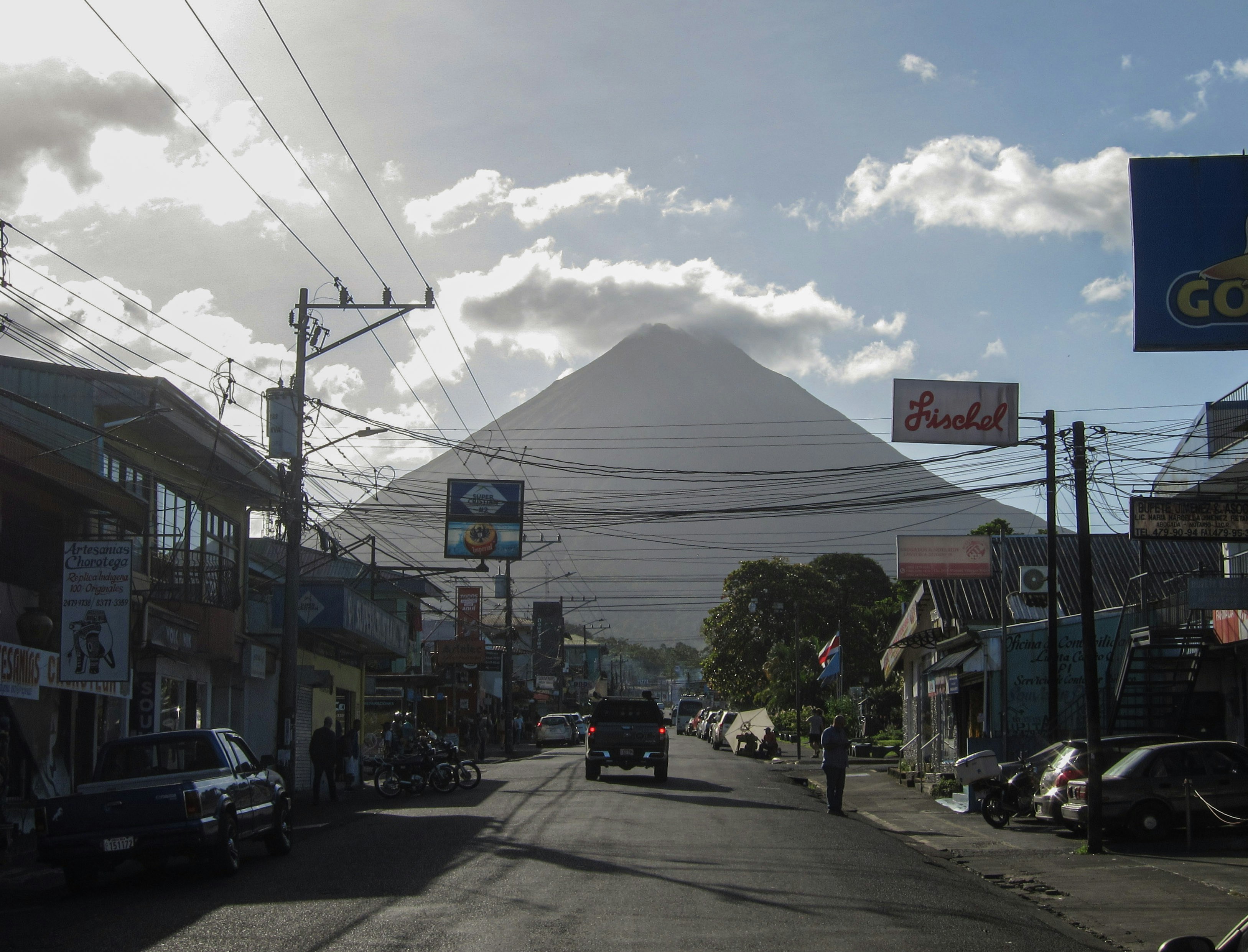 a street with cars parked on the side of it and a mountain in the background